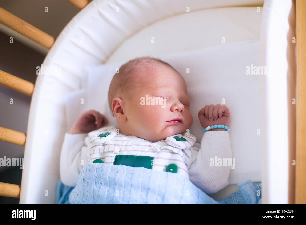 Newborn baby in hospital room. New born child in wooden cosleeper crib