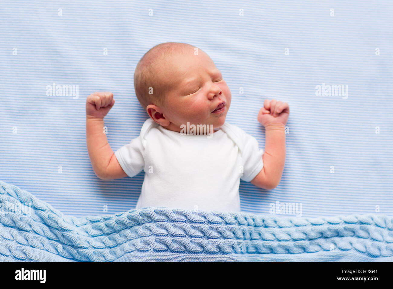 Newborn baby boy in bed. New born child sleeping under a blue knitted