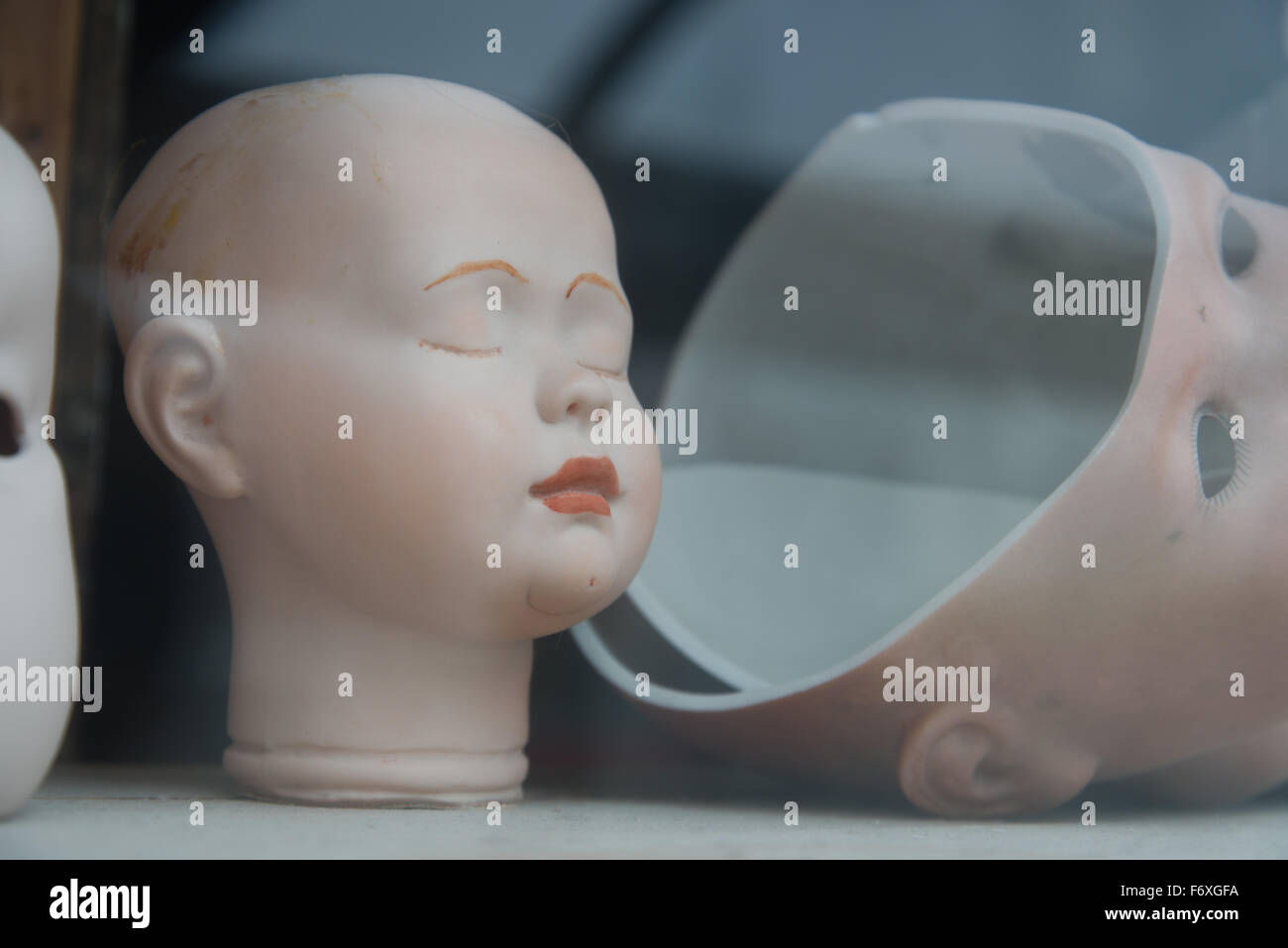 Dolls heads through the window of a doll repair shop Stock Photo Alamy
