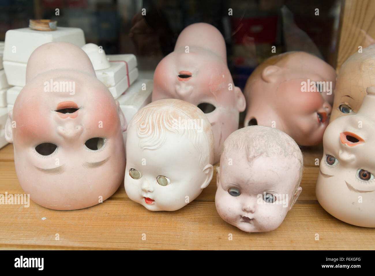 Dolls heads through the window of a doll repair shop Stock Photo