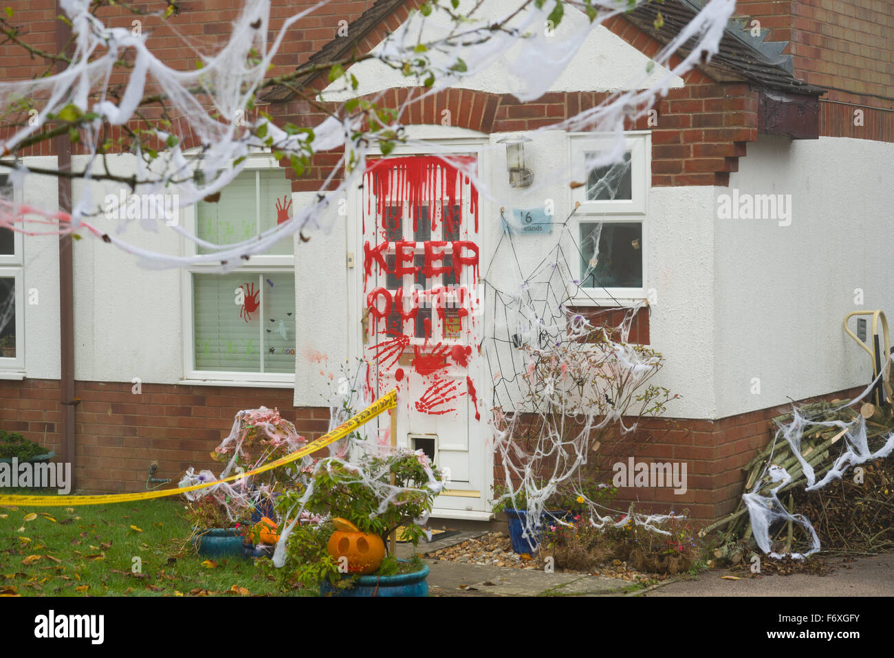 Halloween decorated house with the words 'Keep Out' in red on the front door. Pumpkins and fake spiders web and skeletal hands. Stock Photo