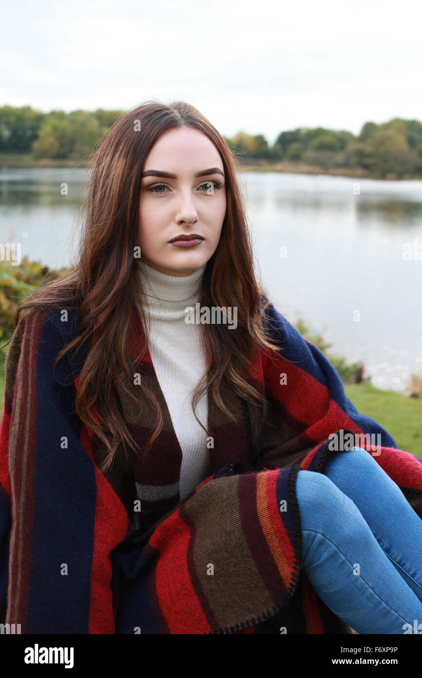 Beautiful young woman sitting in the park with lake in background Stock ...