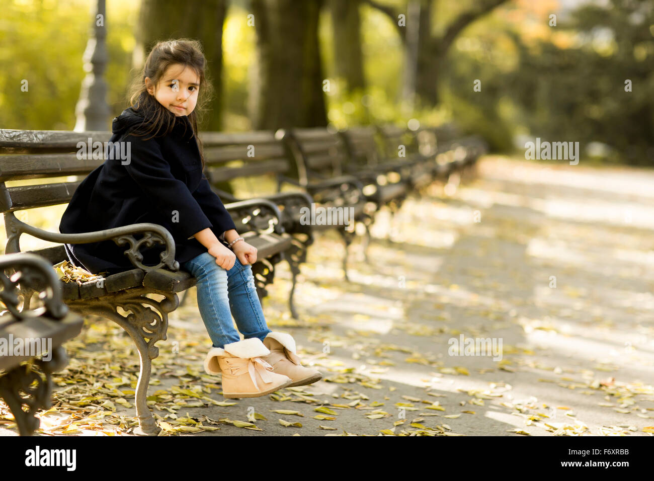 Little girl on the bench in the autumn park Stock Photo - Alamy