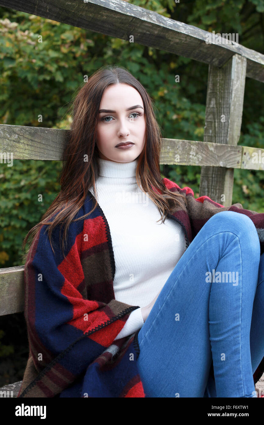Beautiful young woman sitting on a wooden bridge Stock Photo - Alamy