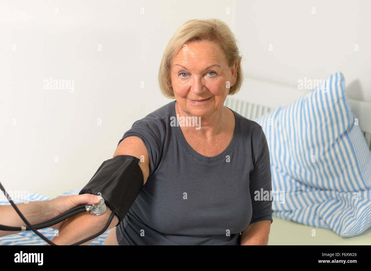 Male nurse or doctor taking a blood pressure reading using a cuff on an elderly lady , close up