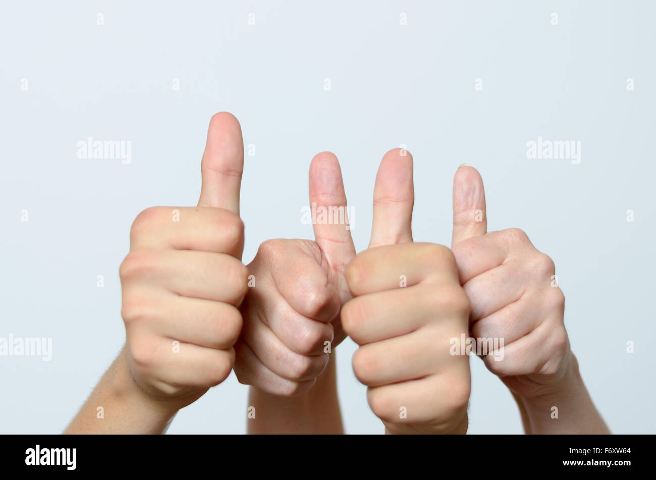 Two motivated people giving a thumbs up gesture with both hands in a row signalling their success, support and approval, close u Stock Photo