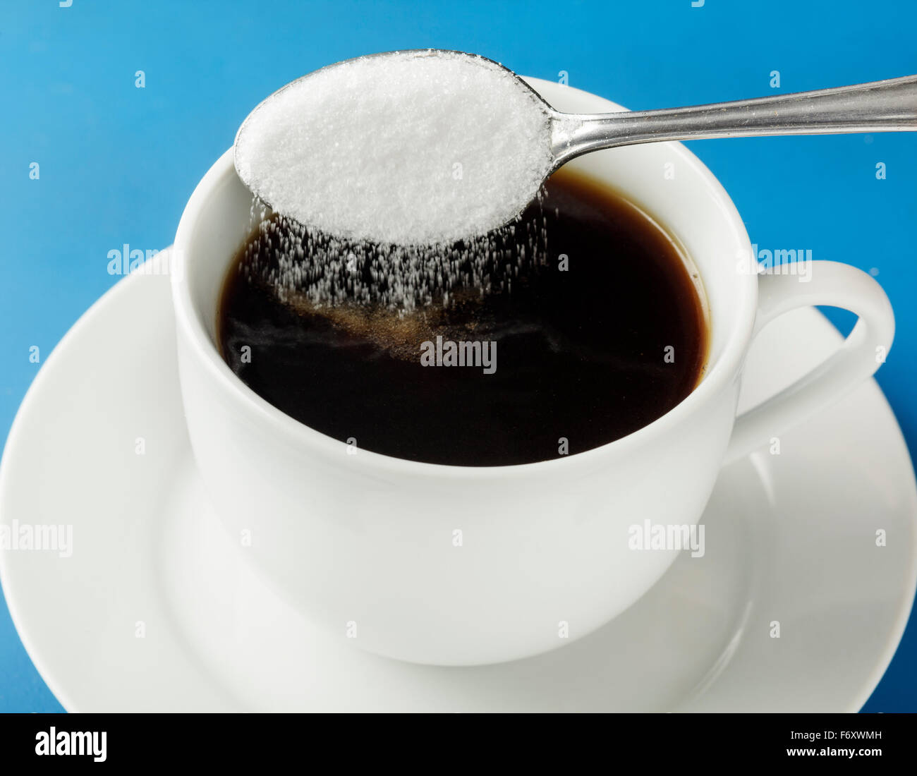 Spoon of sugar being poured into coffee cup Stock Photo