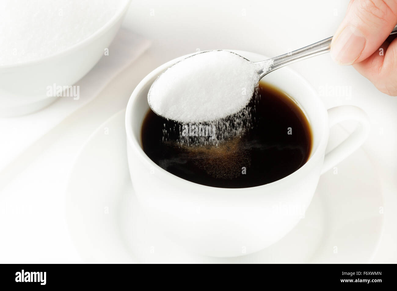 Spoon of sugar being poured into coffee cup Stock Photo