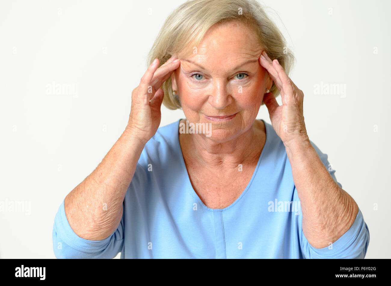 Senior woman wearing blue shirt while showing her face, effect of aging caused by loss of elasticity, close-up Stock Photo