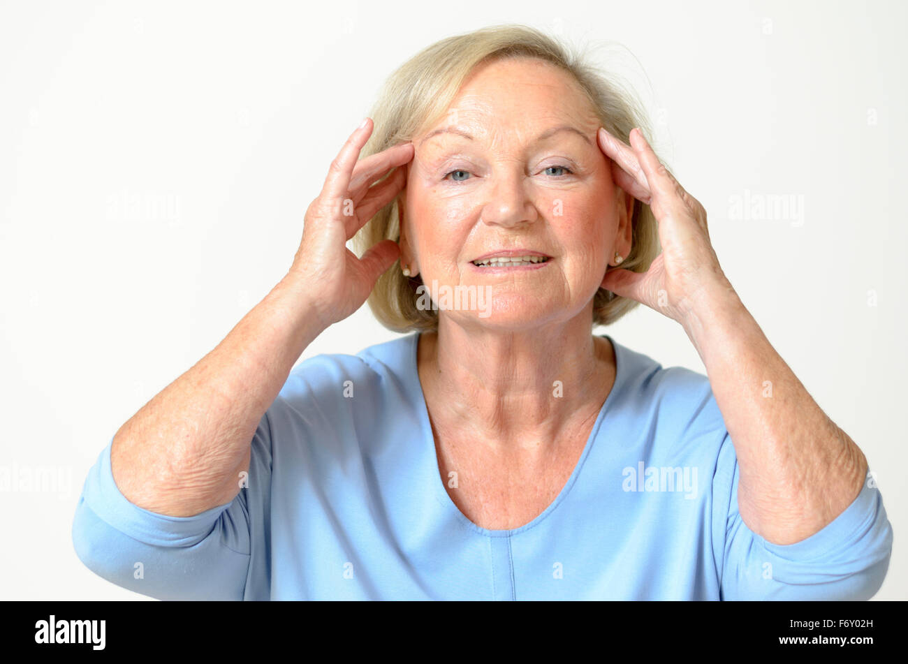Senior woman wearing blue shirt while showing her face, effect of aging caused by loss of elasticity, close-up Stock Photo