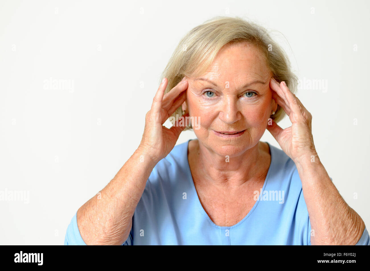 Senior woman wearing blue shirt while showing her face, effect of aging caused by loss of elasticity, close-up Stock Photo
