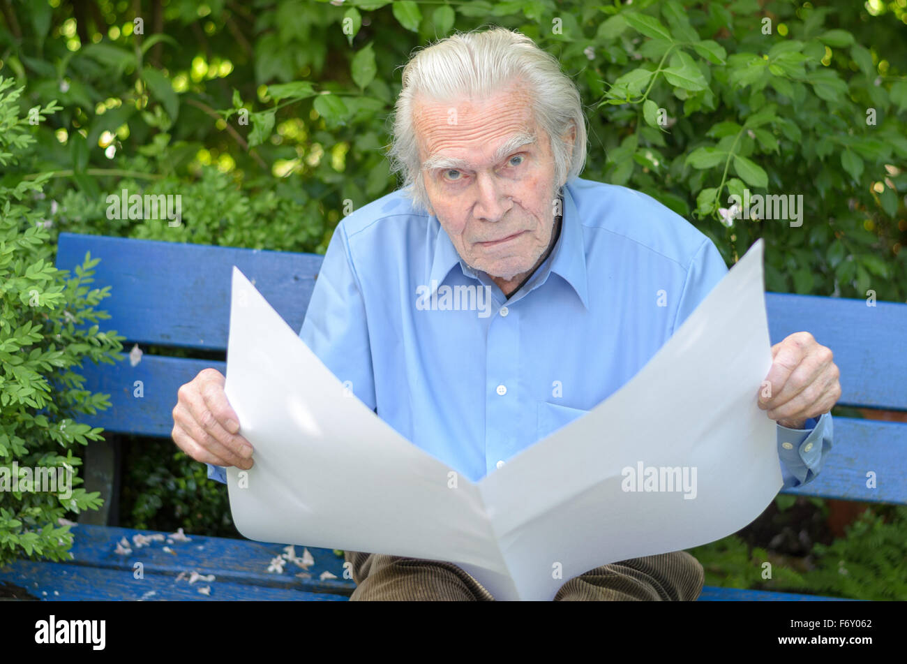Elderly man sitting alone on a blue wooden bench in the park while ...