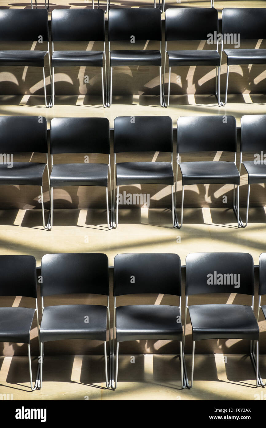 Rows of empty seats in a meeting room as the sun shines through and leaves interesting highlights. Stock Photo