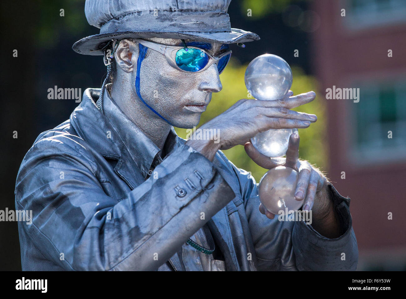 A street performer gazes at large glass marbles during his act at the Saturday Market in Portland, Oregon. Stock Photo