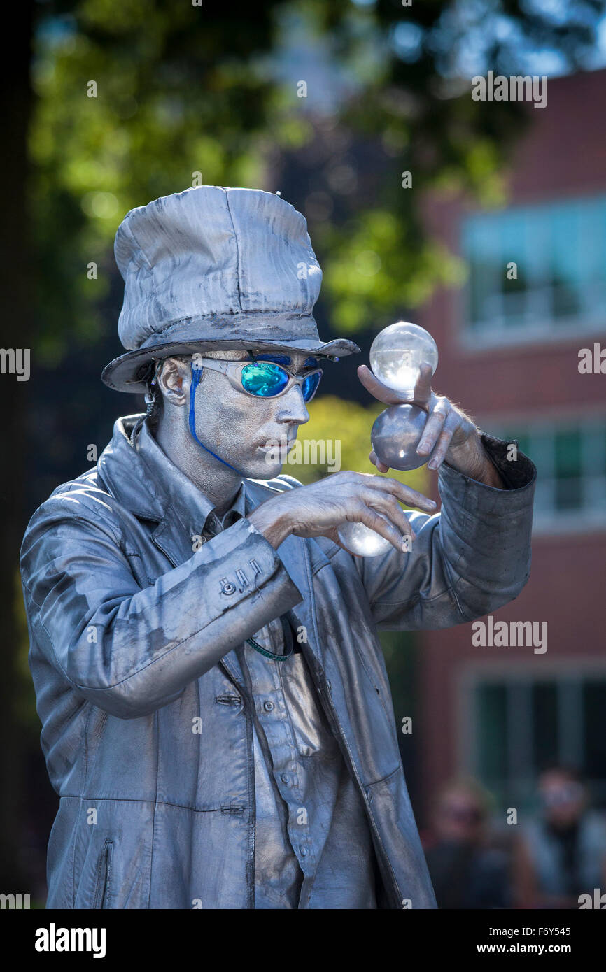 A street performer gazes at large glass marbles during his act at the Saturday Market in Portland, Oregon. Stock Photo