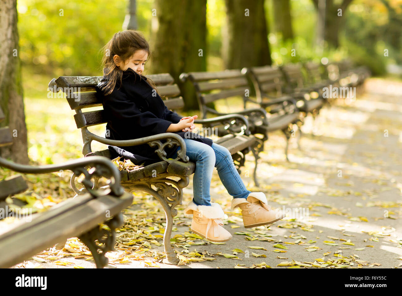 Little girl on the bench in the autumn park Stock Photo - Alamy