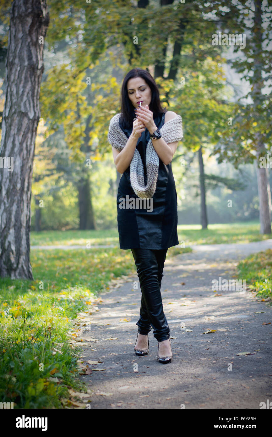 Attractive black hair woman enjoying smoking cigarette in park Stock Photo