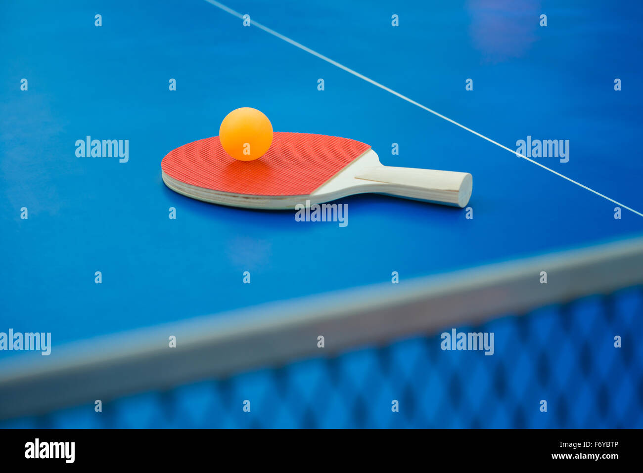 pingpong racket and ball and net on a blue pingpong table vertical Stock Photo