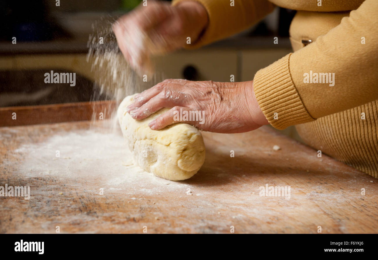 Woman preparing kopytka dough on wooden bakeboard in the kitchen, Polish traditional food pieces lying on bakeboard, home made Stock Photo