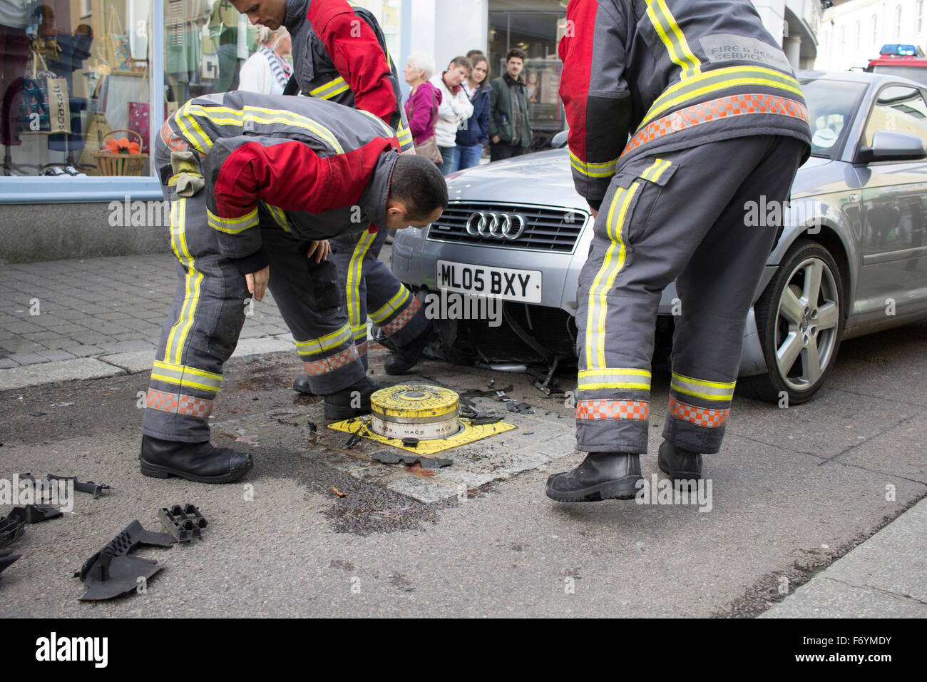 Firemen come to remove a silver Audi impaled on automatic rising bollard in Castle Street, Falmouth. 1st November 2015. Stock Photo