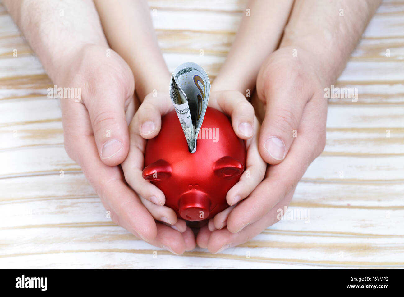 close up of father and son hands holding red piggy bank Stock Photo - Alamy