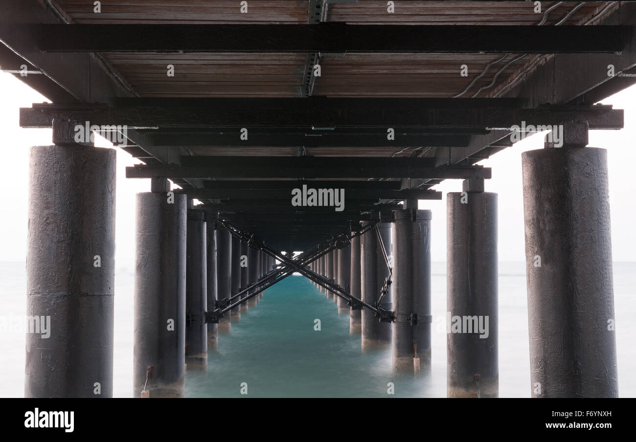Rusty metallic  pier from sea level in horizontal composition creating a diagonal directive tunnel. Stock Photo