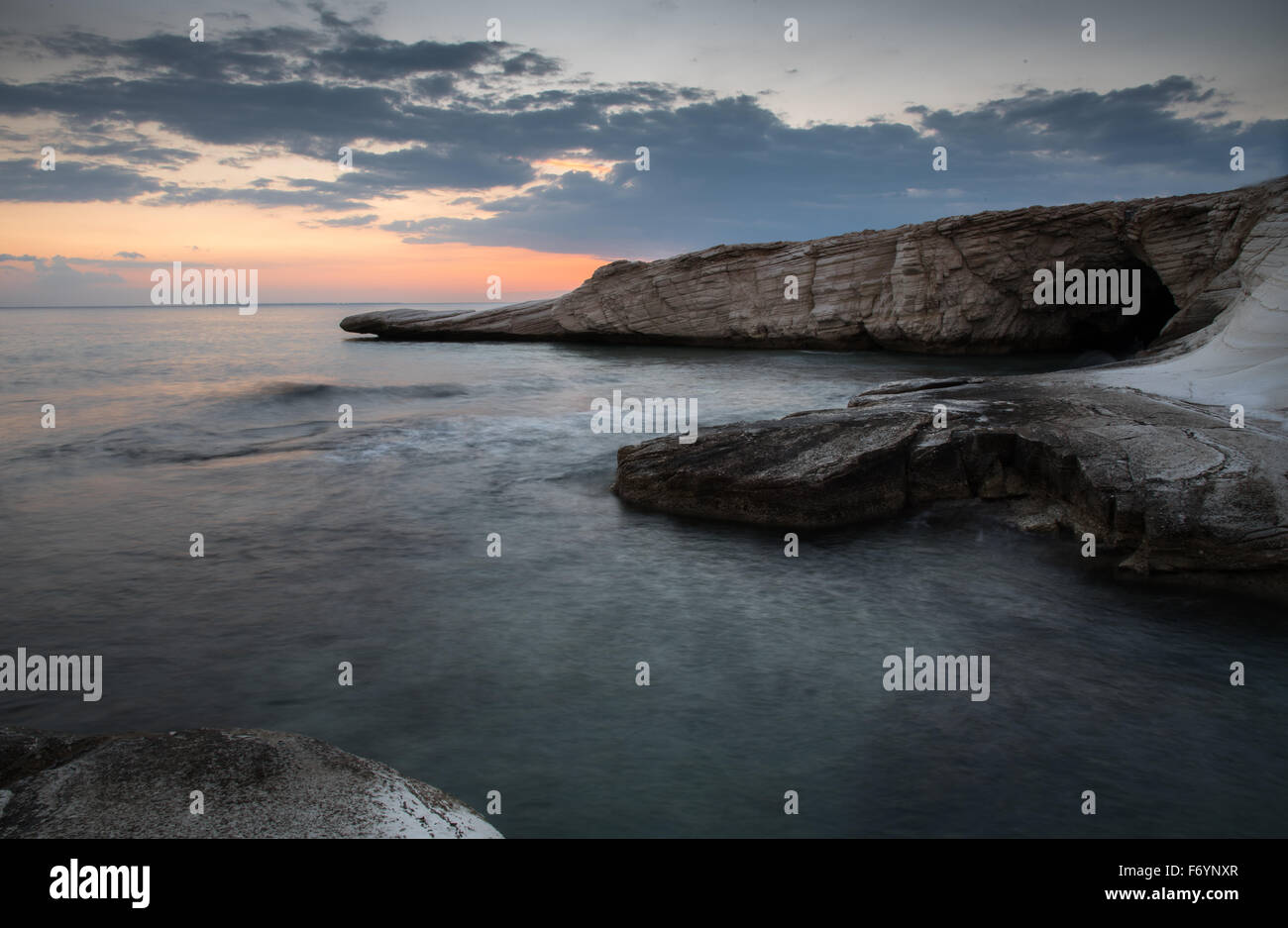 Dramatic Sunset in the in the ocean over a rocky  coast. Image taken  at Kavernos beach in Limassol Cyprus. Stock Photo