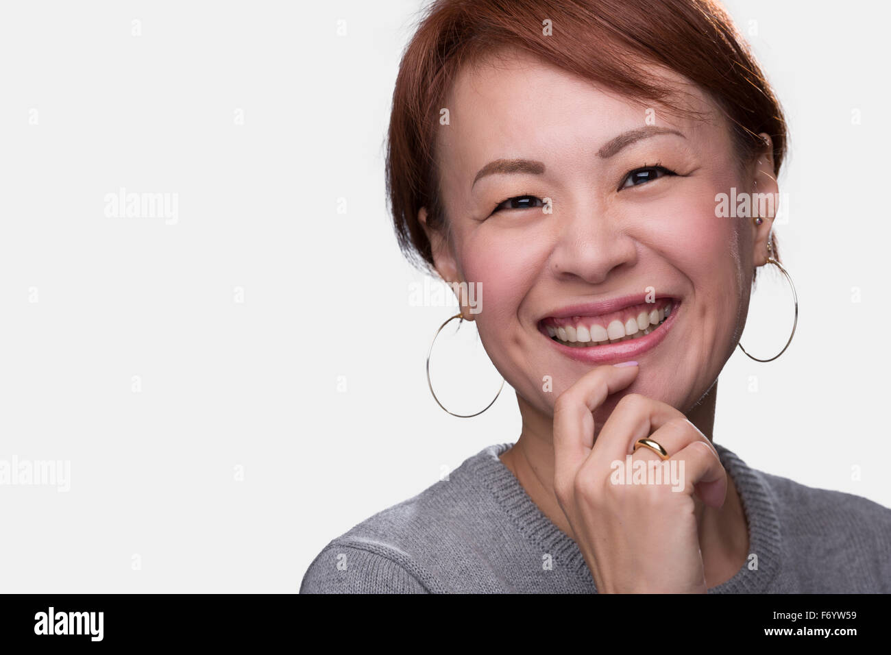 A headshot of a smiling middle aged Japanese woman on a white background. Stock Photo
