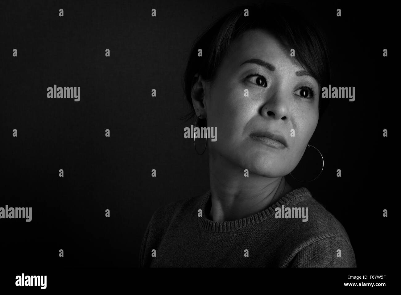 A black and white headshot of a sad looking middle aged Japanese woman. Stock Photo