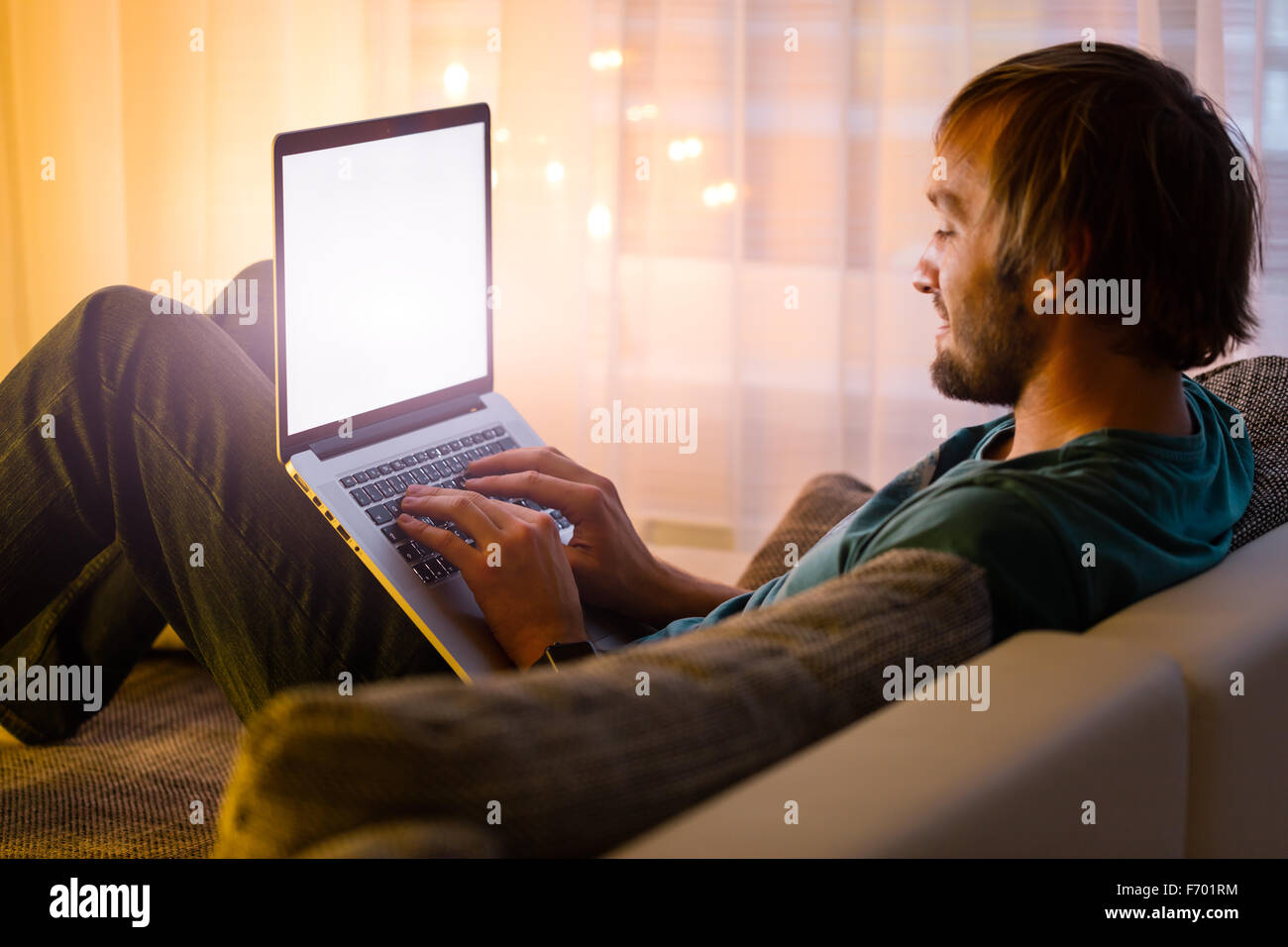 Man working on laptop in cozy home interior Stock Photo - Alamy
