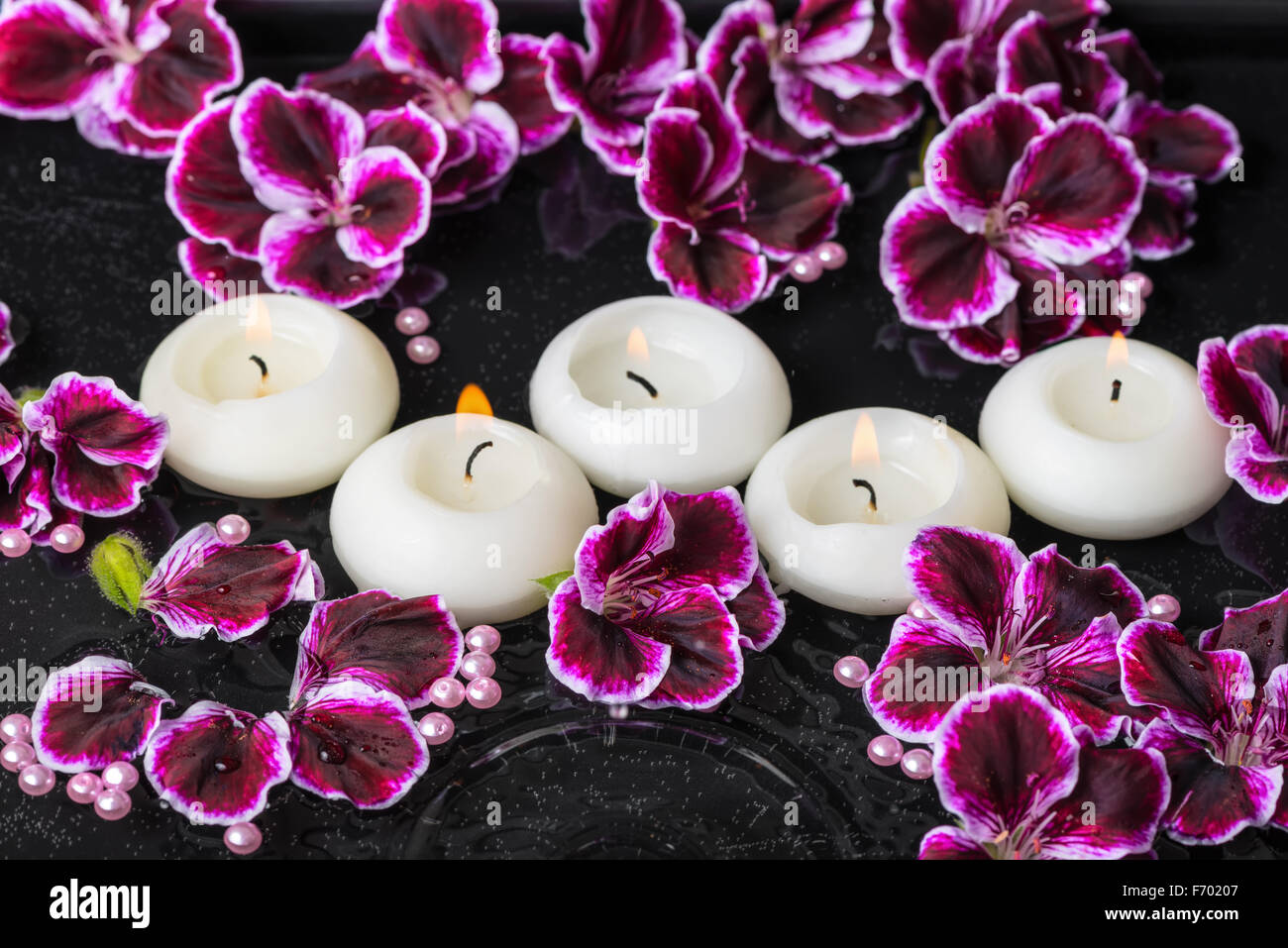 beautiful spa still life of geranium flower and candles in ripple ...