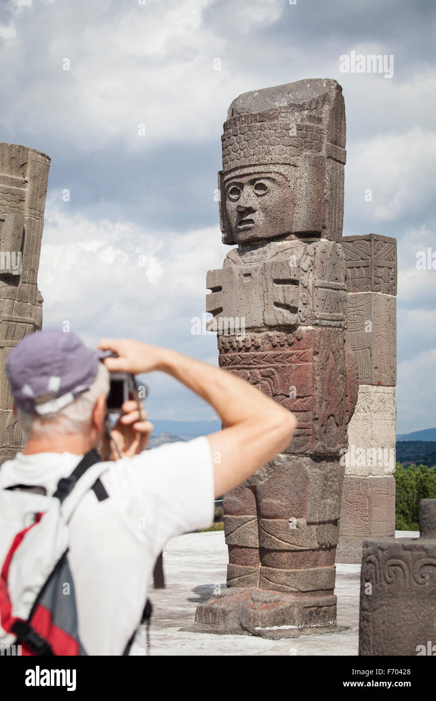 Tourist  an Atlante on top of the main pyramid at the Toltec ruins of Tula, Mexico. Stock Photo
