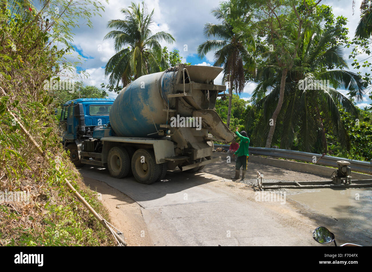 DONSOL, PHILIPPINES - JUNE 2, 2015: Unknown road workers with a cement truck building a new forest road in the philippines Stock Photo