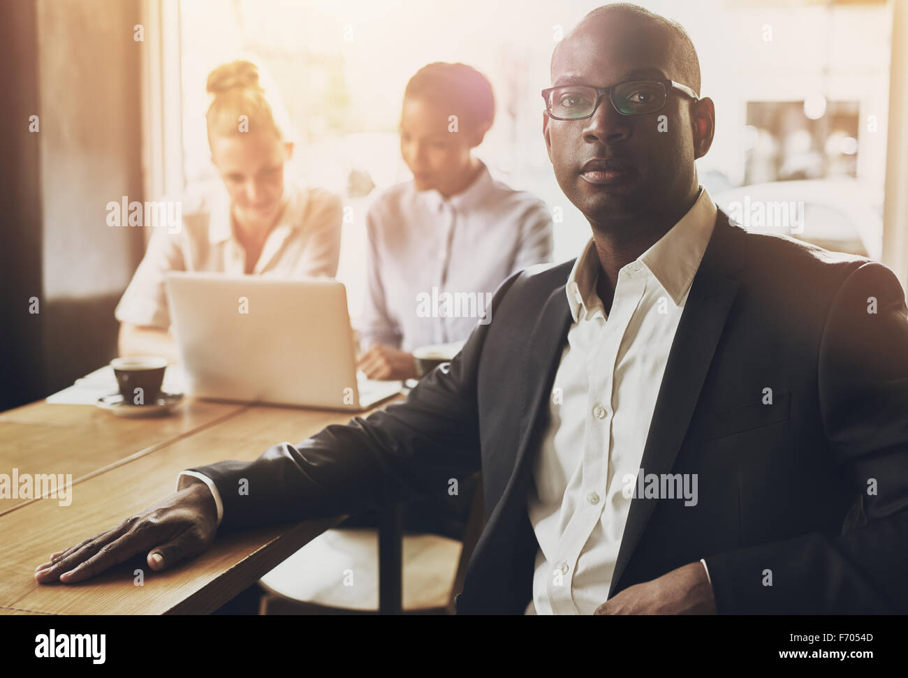 Relaxed black business man at office, people in background Stock Photo