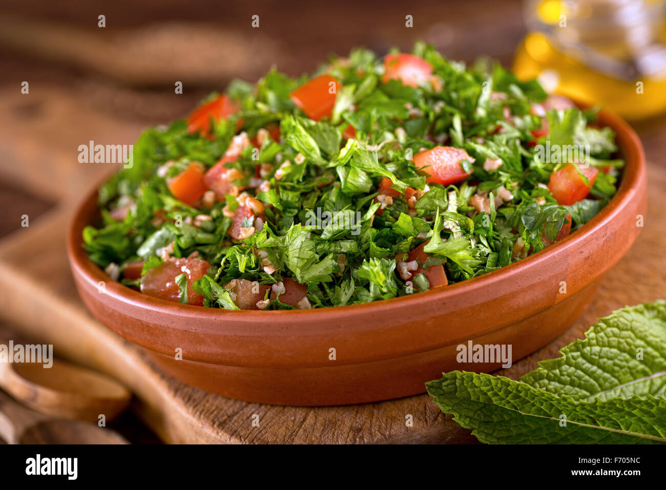 A bowl of delicious fresh tabouli with parsley, mint, tomato, onion, olive oil, lemon juice, and bulgar wheat. Stock Photo