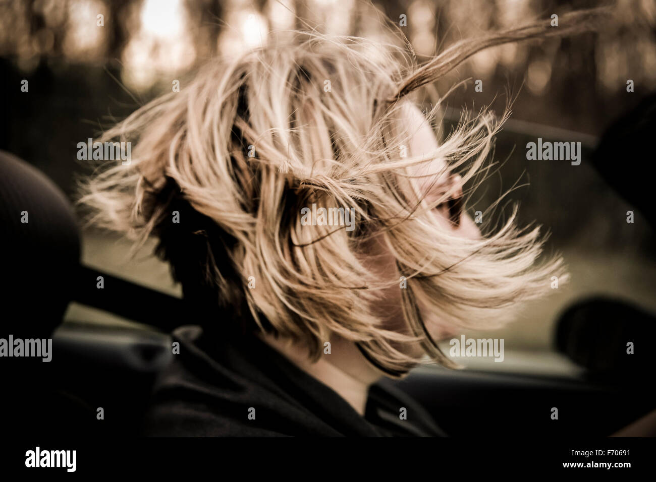 Woman driving convertible car in summer with hair blowing in the wind
