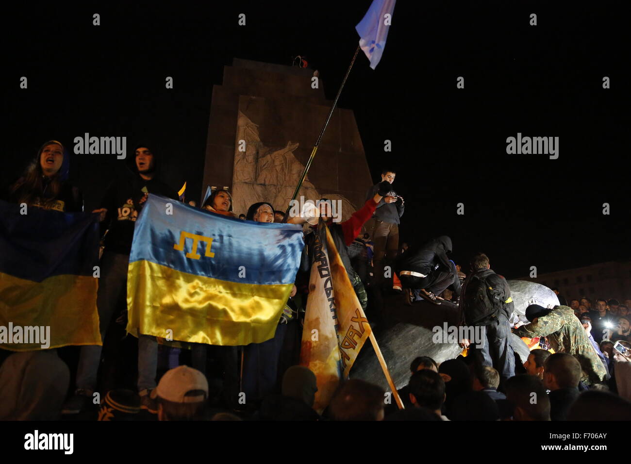 Ukrainianian protesters, some holding a Tartar flag to represent Crimea, celebrate after cutting down the Lenin Statue on Freedom Square in Kharkiv, Ukraine, in a predominately Russian speaking area of the country. The statue, one of the largest in Ukraine, is on the largest square in the country. Stock Photo