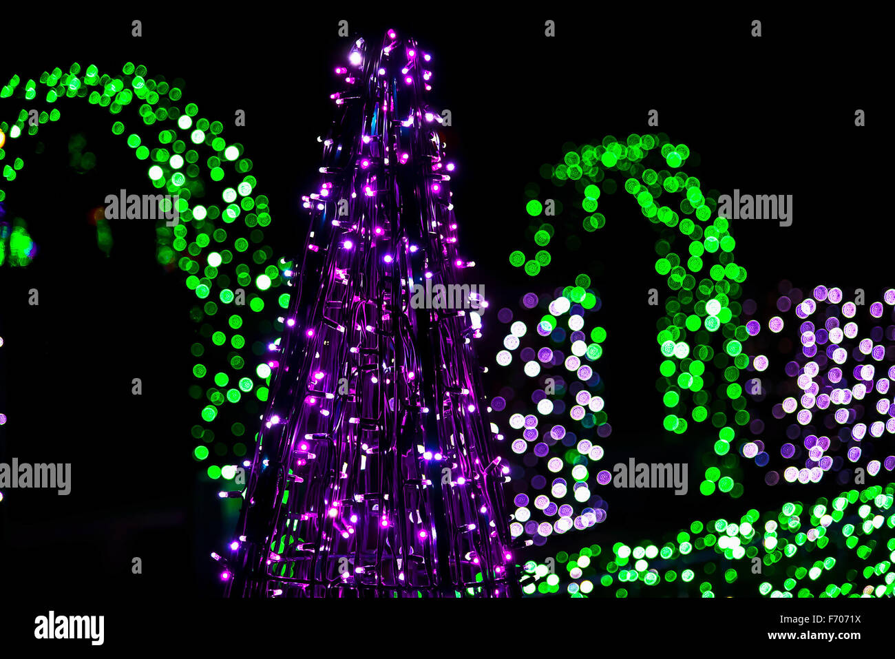 Construction of Christmas Tree from Garlands against Colorful Lights at Night Stock Photo