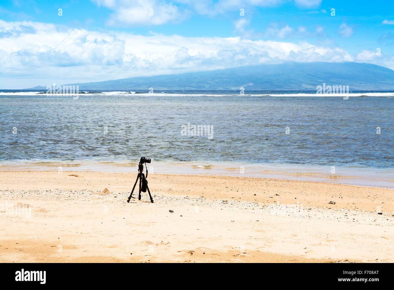 A camera and tripod on a deserted beach set to capture the ambiance of ...