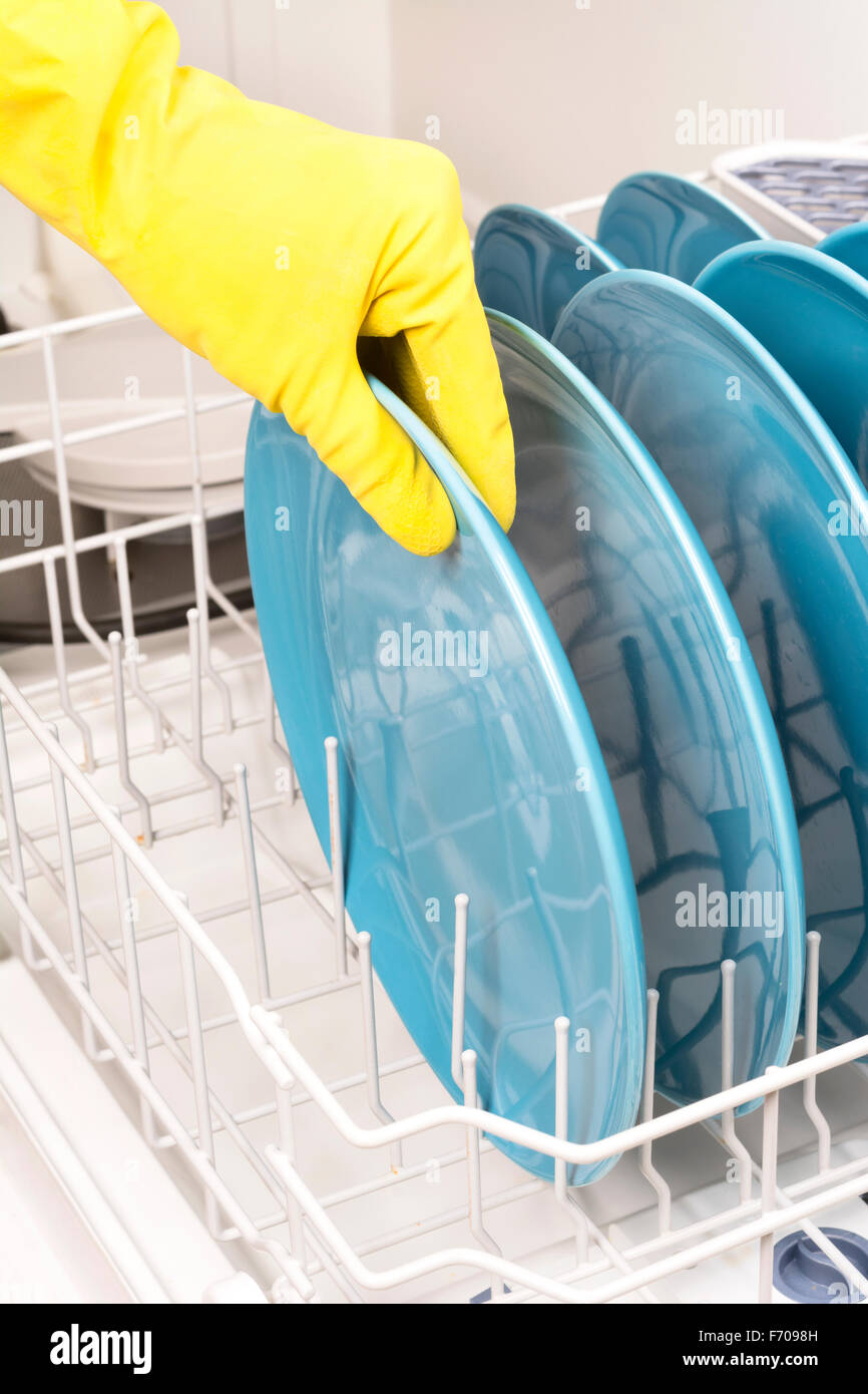 A woman removes dishes after they are finished being washed in a dishwasher Stock Photo