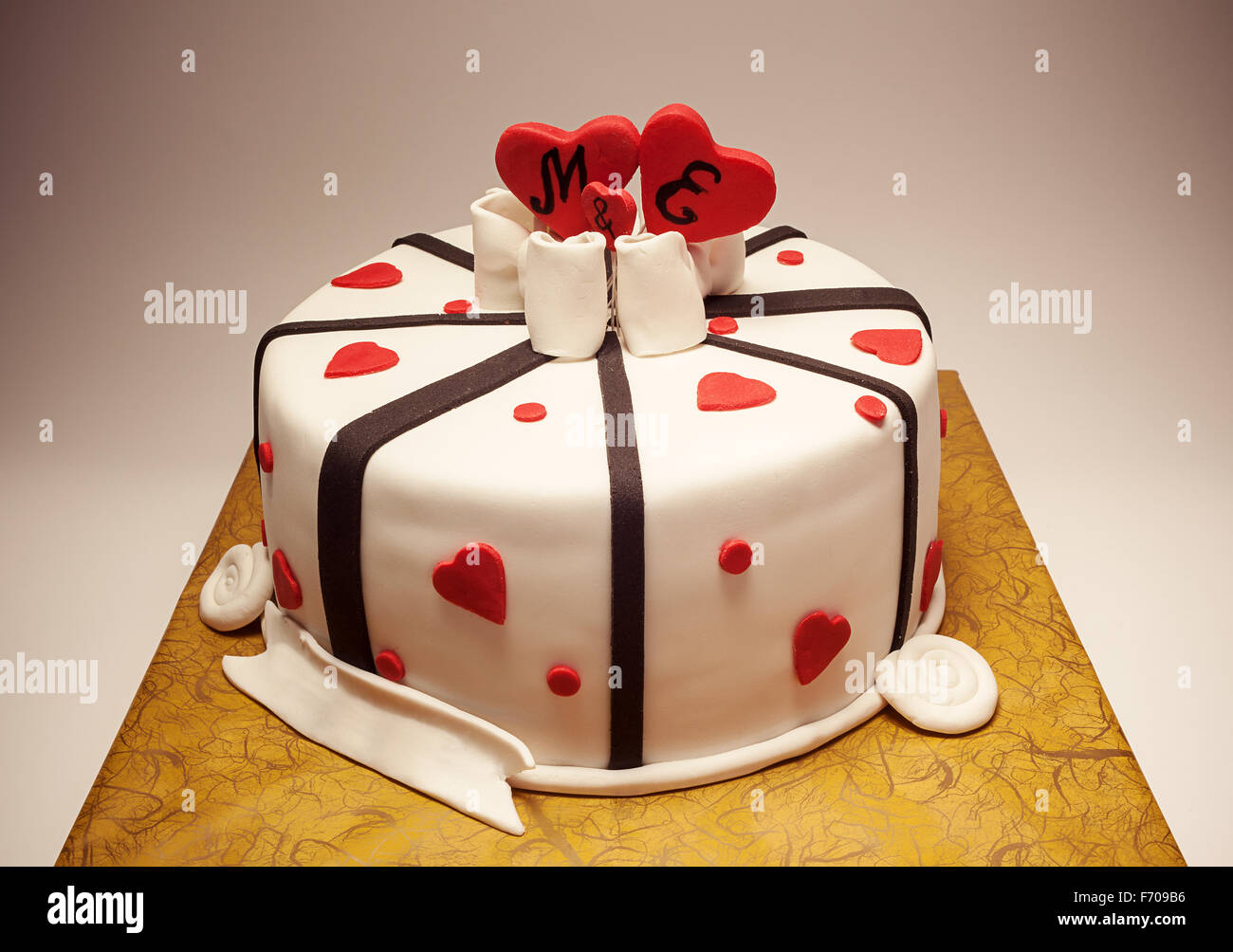 Anniversary cake decoration with red hearts and black ribbons. Stock Photo