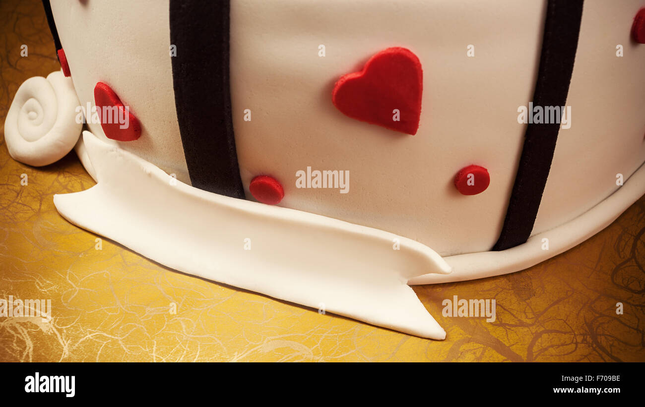 Anniversary cake decoration with red hearts and black ribbons. Stock Photo