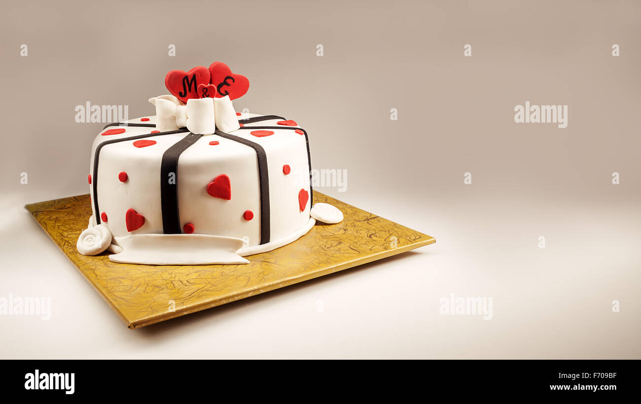 Anniversary cake decoration with red hearts and black ribbons. Stock Photo