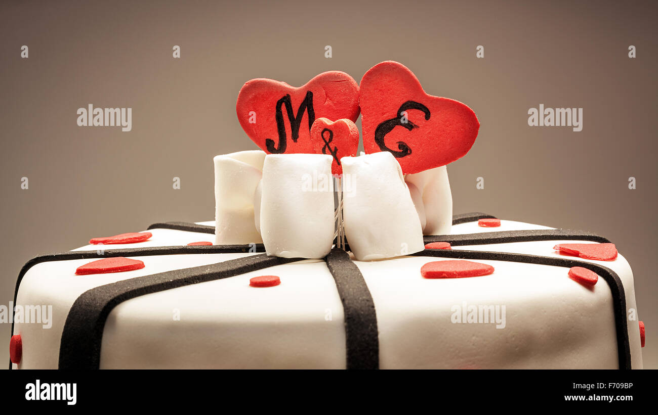 Anniversary cake decoration with red hearts and black ribbons. Stock Photo