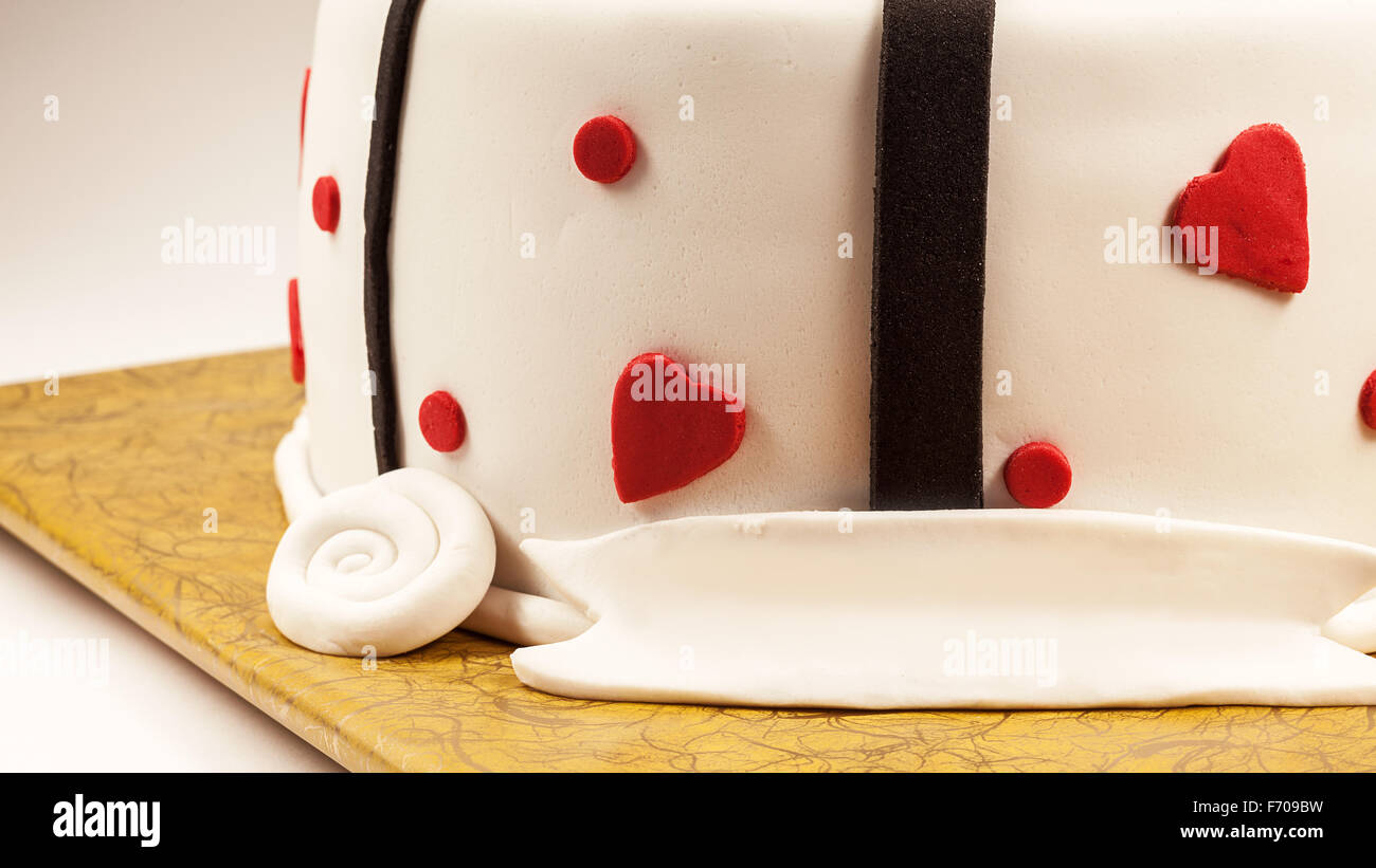 Anniversary cake decoration with red hearts and black ribbons. Stock Photo