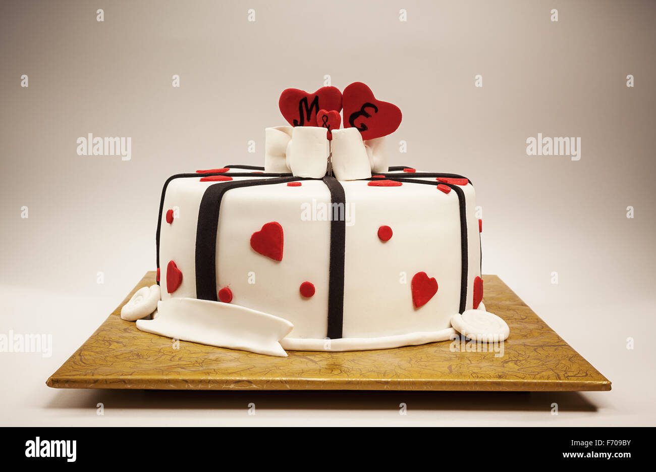 Anniversary cake decoration with red hearts and black ribbons. Stock Photo