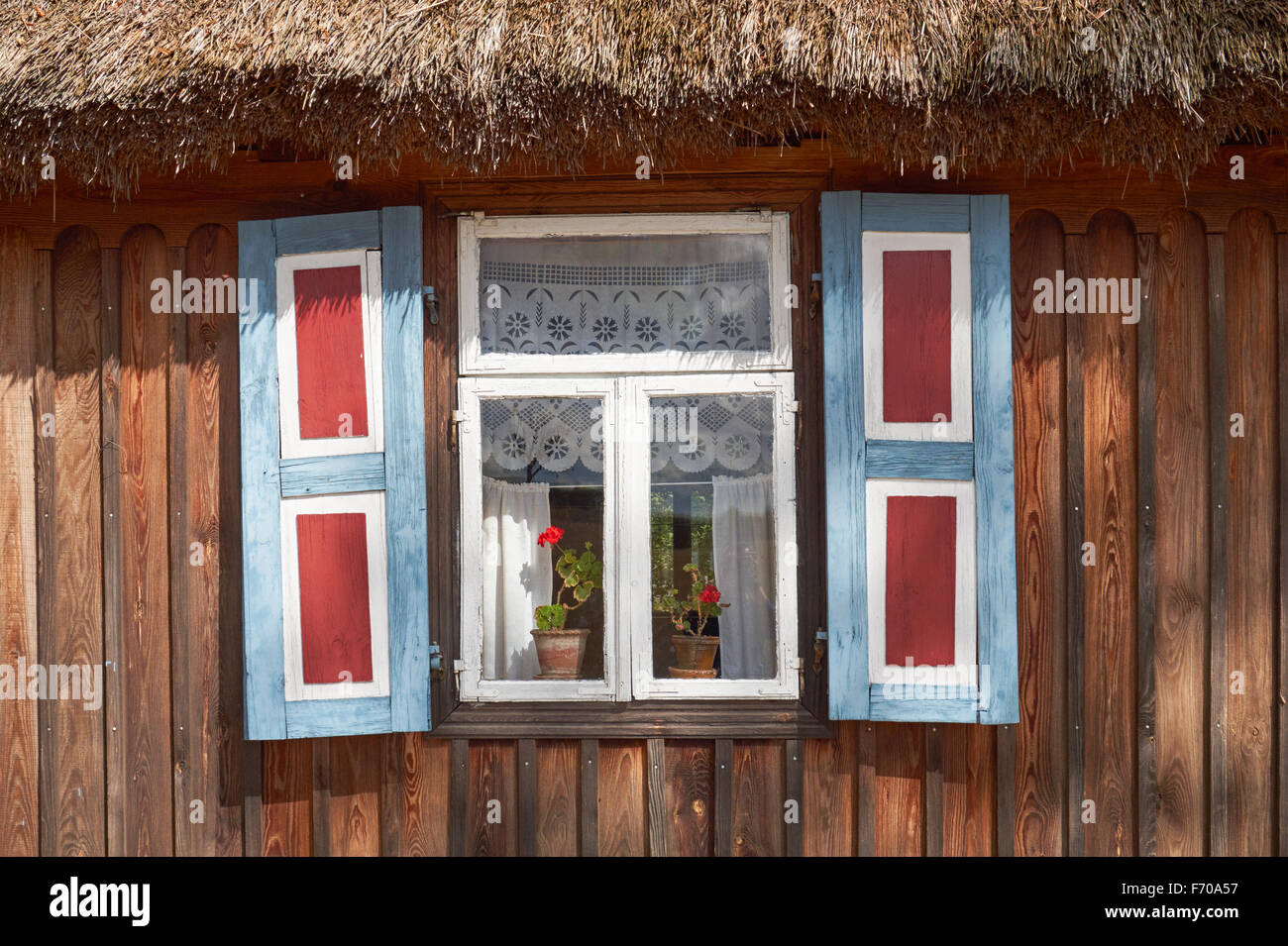 The Museum of the Mazovian Countryside in Sierpc, Poland. Old wooden peasant thatched farmhouse with decorative shutters. Stock Photo