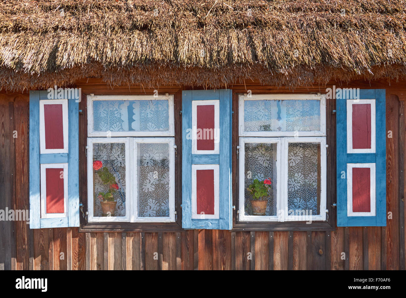 The Museum of the Mazovian Countryside in Sierpc, Poland. Old wooden peasant thatched farmhouse with decorative shutters. Stock Photo