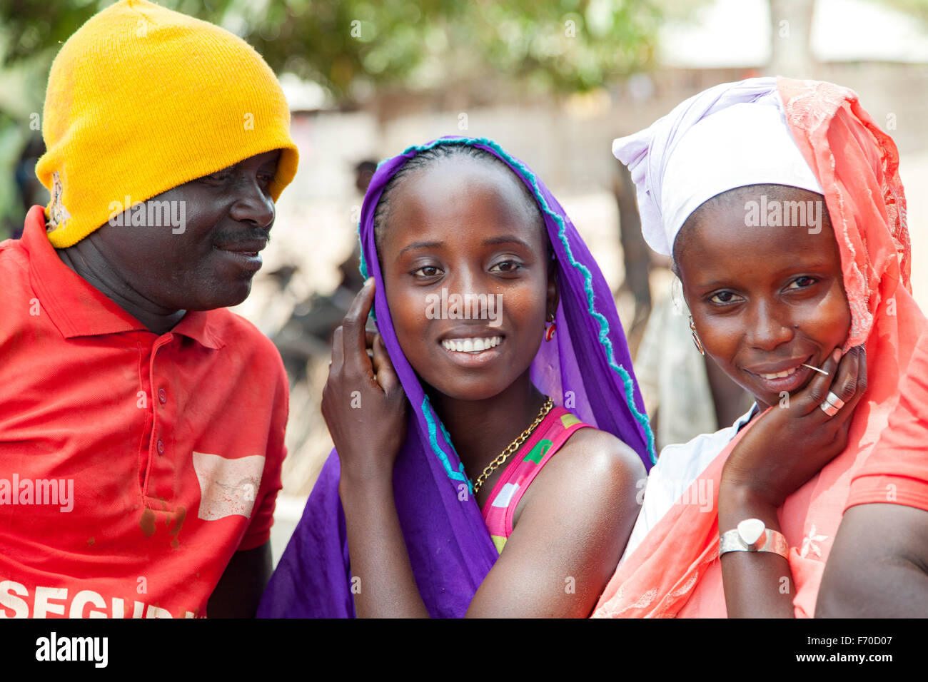 Gabu, Guinea-Bissau - May 10, 2014: Man trying to flirt with two African girls. Daily scenes from rural Guinea-Bissau Stock Photo