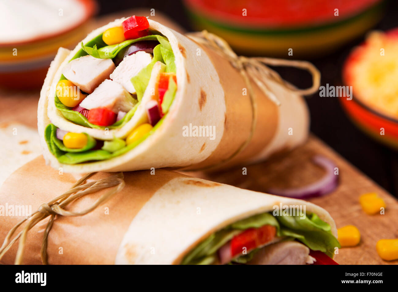 Healthy chicken wraps on a rustic chopping board. Stock Photo